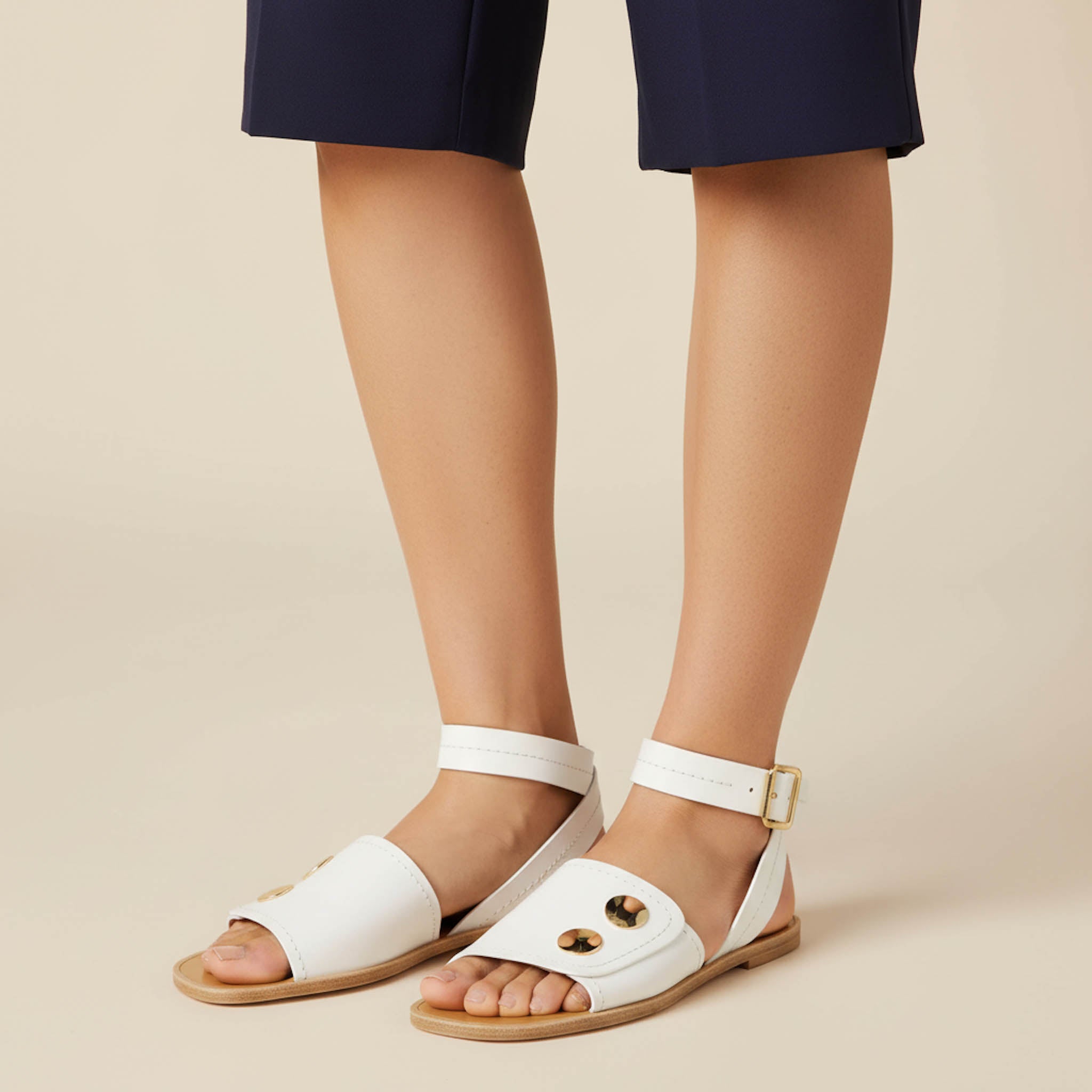 Open toe leather sandals with ankle strap and gold accents from Italy sold in the United States.