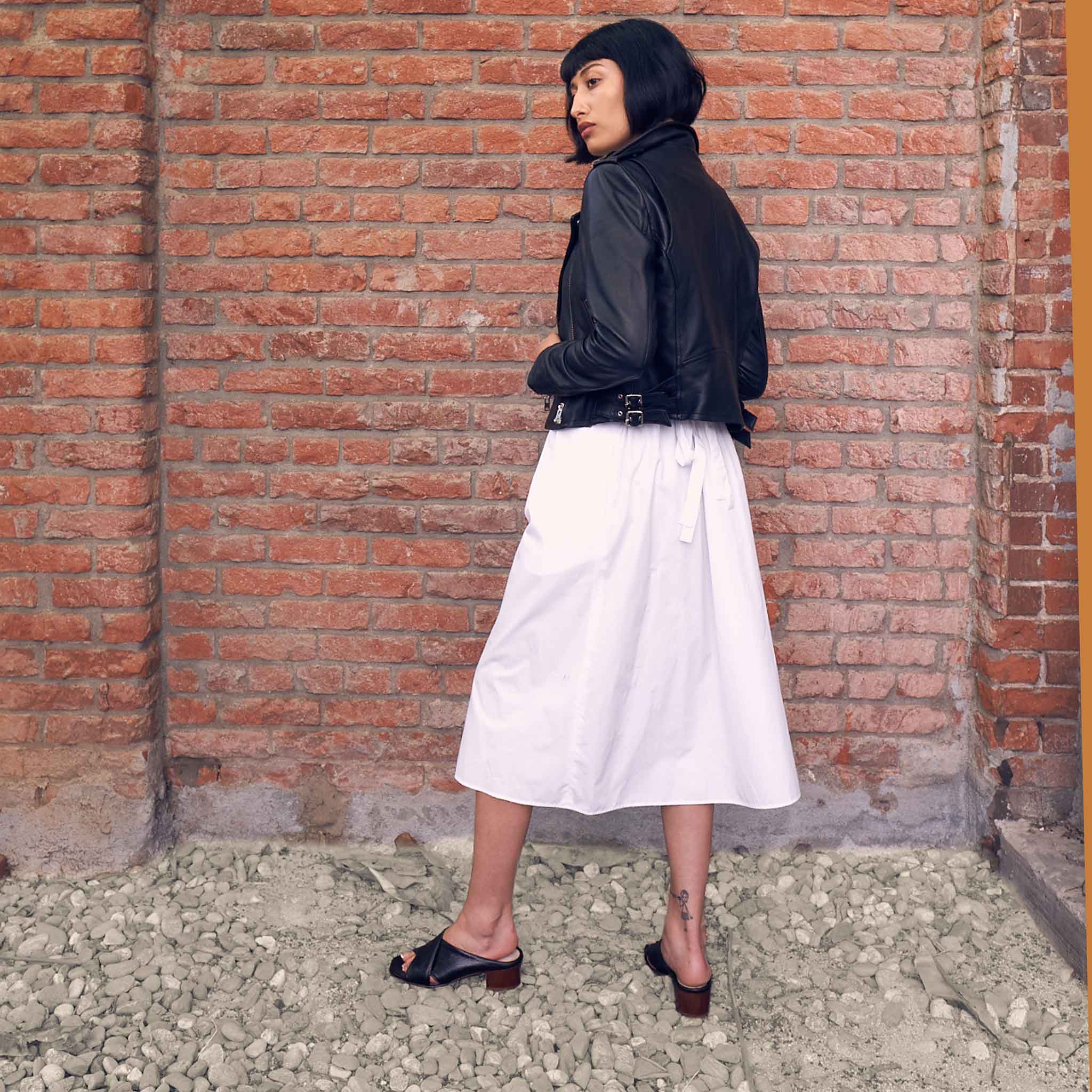 black leather open toe slide heels styled with white skirt and black leather biker jacket