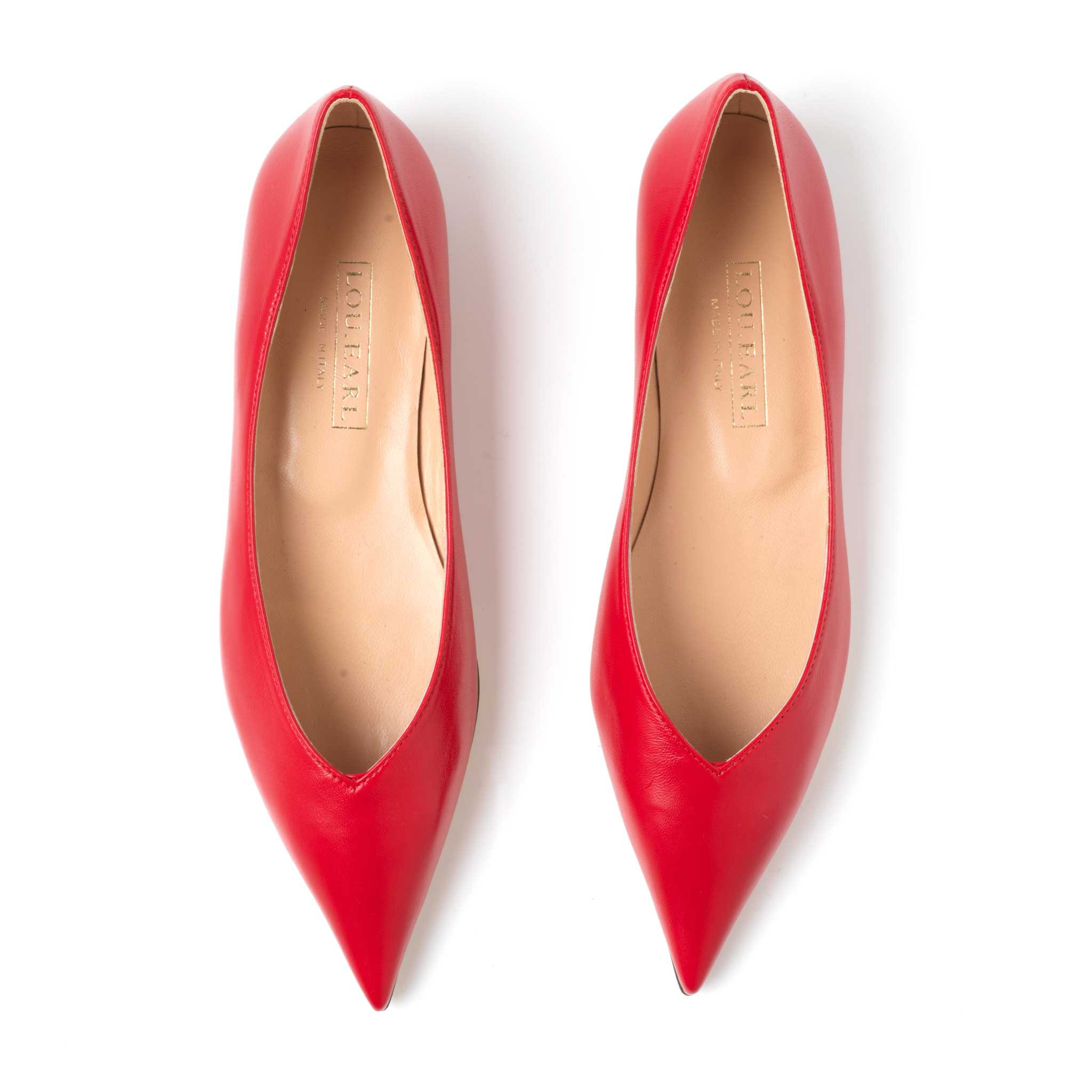 a pair of pointed toe slip on red shoes with a neutral leather color lining and gold logo