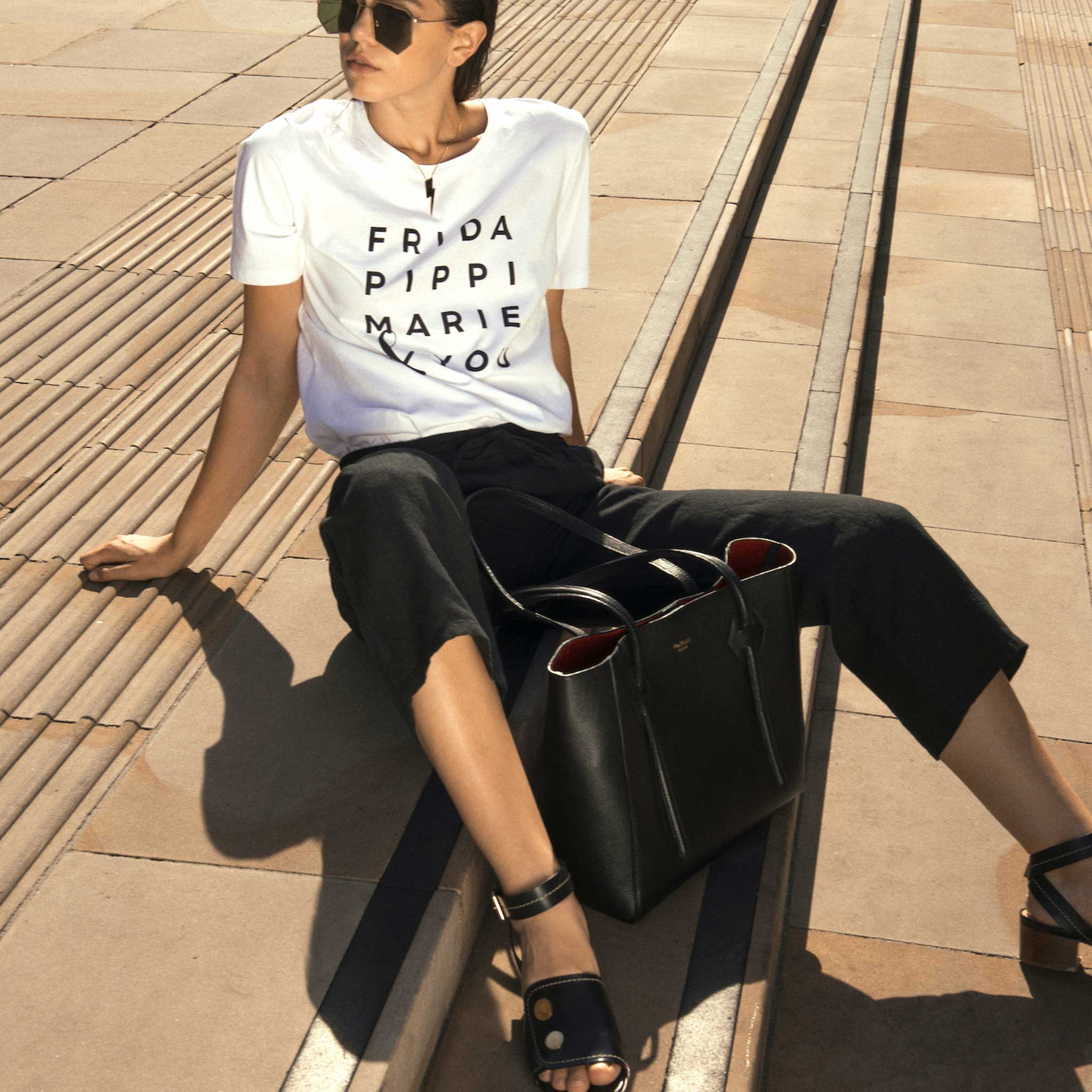 model sitting on steps wearing white t shirt, black pants and black leather 2 inch stacked heel sandals